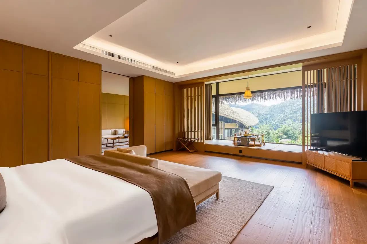 A calm villa bedroom with a wide window toward the mountain landscape
