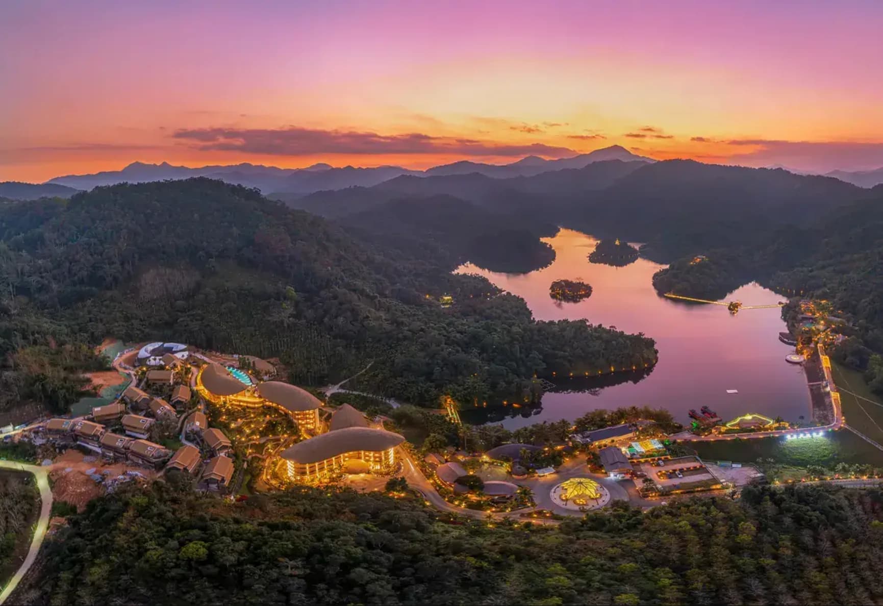 Aerial view across Jade Island, its lake and the surrounding mountain rainforest at sunset