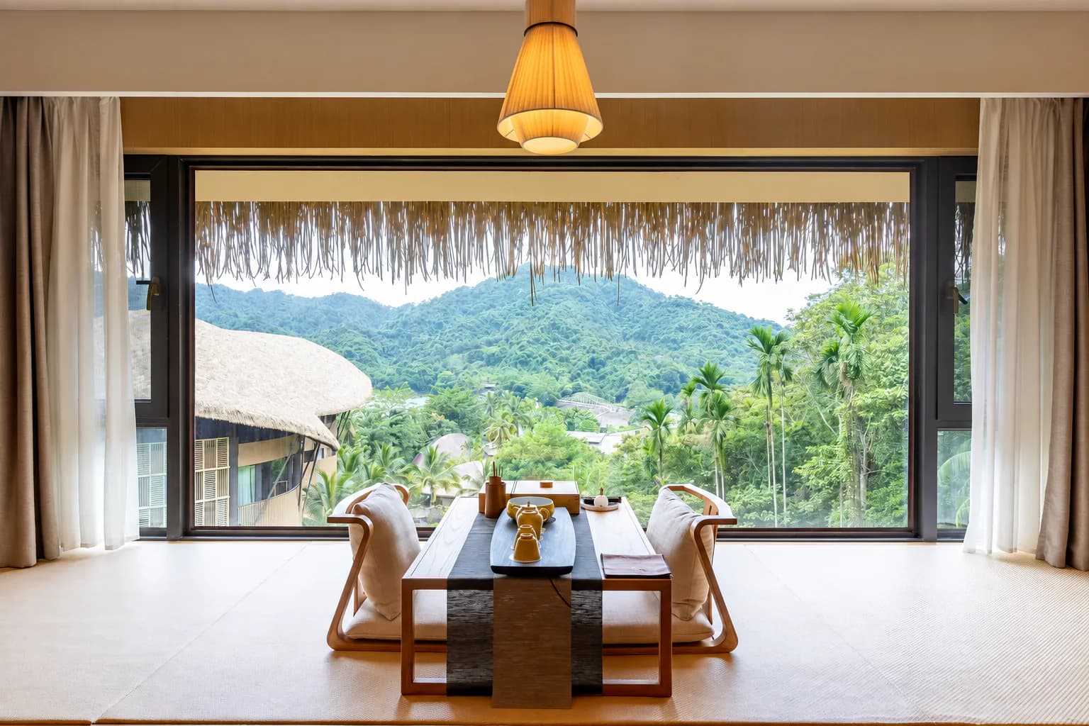A low tea table beside a wide window overlooking tropical mountains